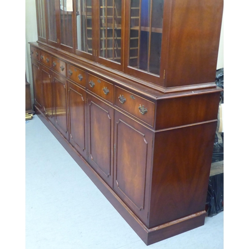 57 - A 20thC reproduction of a Georgian mahogany library bookcase, the upper section with three pairs of ... 