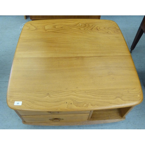 68 - An Ercol blonde elm coffee table, incorporating a pair of offset box drawers with recessed handles, ... 