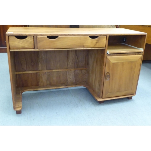 79 - An Ercol honey coloured elm home office desk, comprising two frieze drawers and a slide, one an offs... 