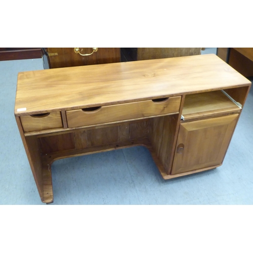 79 - An Ercol honey coloured elm home office desk, comprising two frieze drawers and a slide, one an offs... 