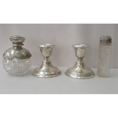 84 - A pair of loaded silverr dwarf candlesticks; a decoratively cast glass dressing table bottle with an... 