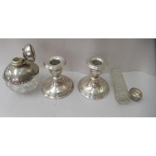 84 - A pair of loaded silverr dwarf candlesticks; a decoratively cast glass dressing table bottle with an... 