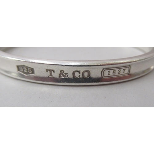 90 - Tiffany & Co silver, viz. a bangle, a band ring and a keyring, on a chain label