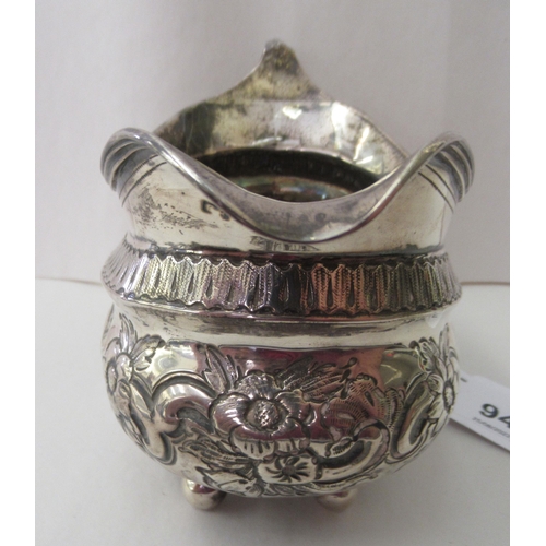 94 - A George III silver oval cream jug, embossed and chased with flora and scrolls, on ball feet  London... 