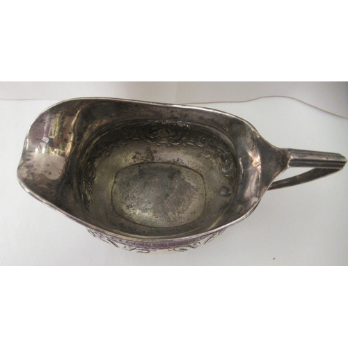 94 - A George III silver oval cream jug, embossed and chased with flora and scrolls, on ball feet  London... 