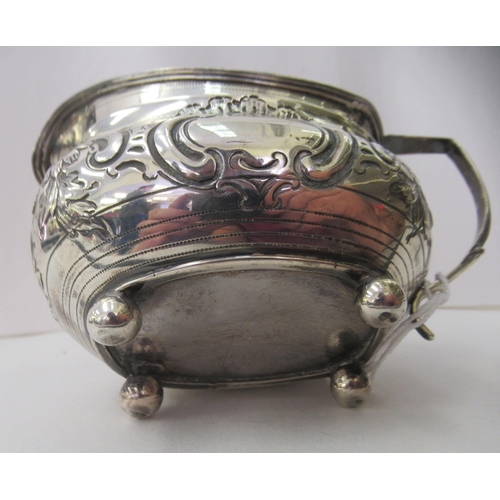 94 - A George III silver oval cream jug, embossed and chased with flora and scrolls, on ball feet  London... 