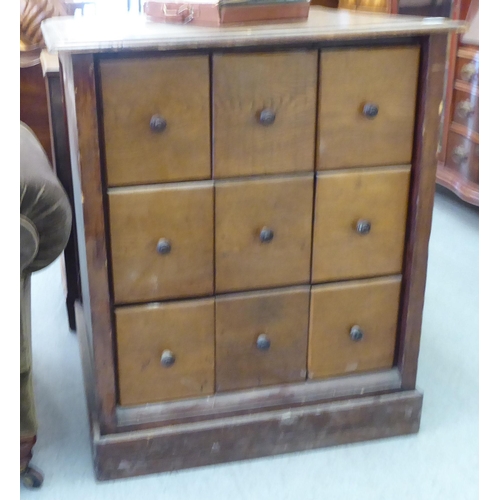 96 - A late 19thC stained pine cabinet, comprising an arrangement of nine equal compartmented box drawers... 