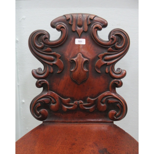 181 - A mid 19thC mahogany hall chair, the boldly, scroll carved, one piece back over a hollow seat, raise... 