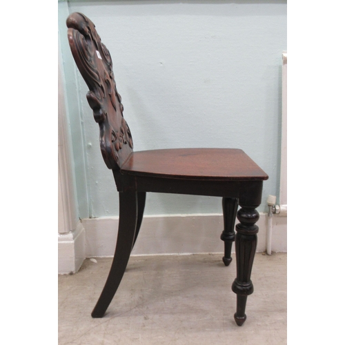 181 - A mid 19thC mahogany hall chair, the boldly, scroll carved, one piece back over a hollow seat, raise... 