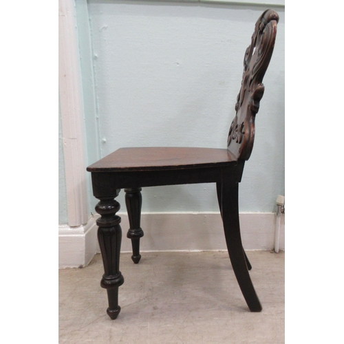 181 - A mid 19thC mahogany hall chair, the boldly, scroll carved, one piece back over a hollow seat, raise... 