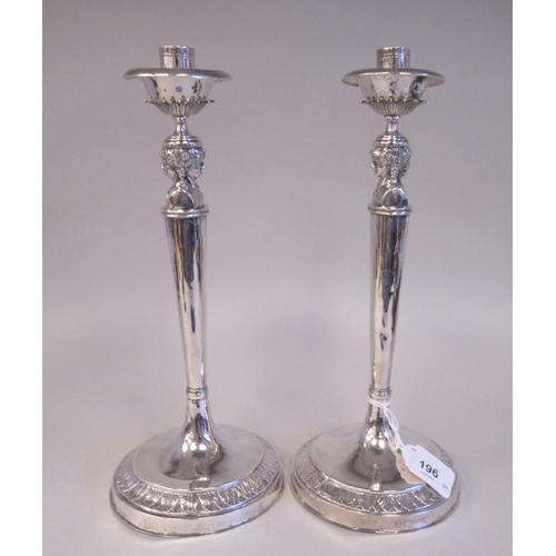 196 - A pair of 19thC Continental silver coloured metal candlesticks, the sockets with bowl shape drip-pan... 