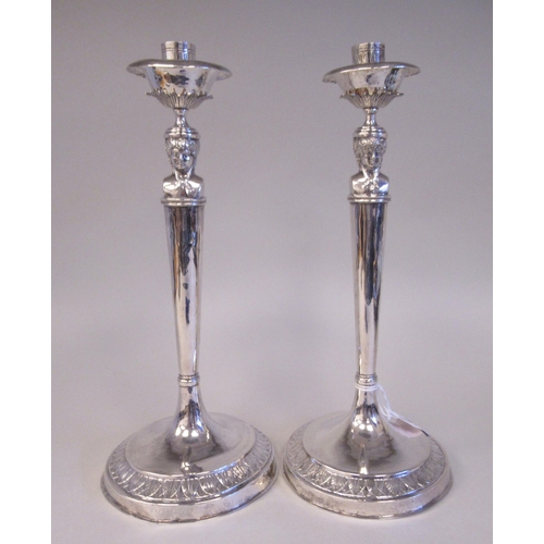 196 - A pair of 19thC Continental silver coloured metal candlesticks, the sockets with bowl shape drip-pan... 