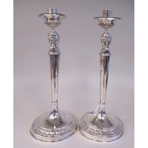 196 - A pair of 19thC Continental silver coloured metal candlesticks, the sockets with bowl shape drip-pan... 