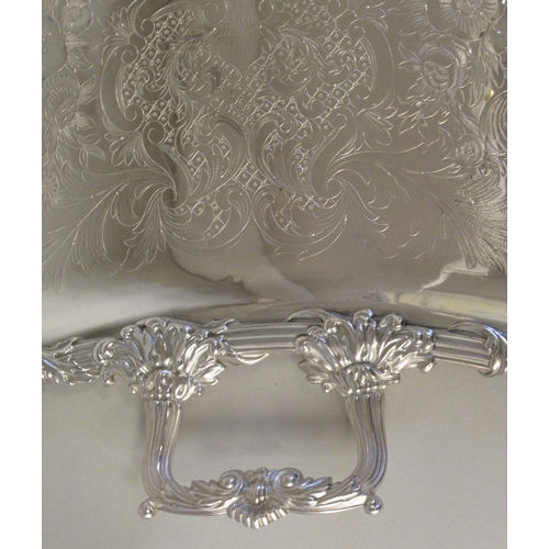 204 - A silver plated twin handled serving tray with incurved sides, a decoratively cast and engraved orna... 