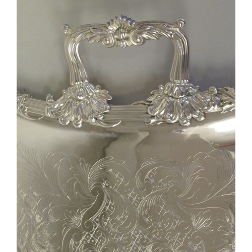 204 - A silver plated twin handled serving tray with incurved sides, a decoratively cast and engraved orna... 