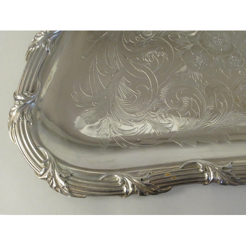 204 - A silver plated twin handled serving tray with incurved sides, a decoratively cast and engraved orna... 