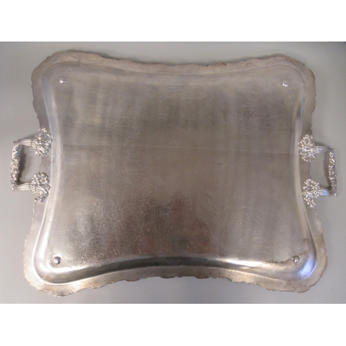 204 - A silver plated twin handled serving tray with incurved sides, a decoratively cast and engraved orna... 