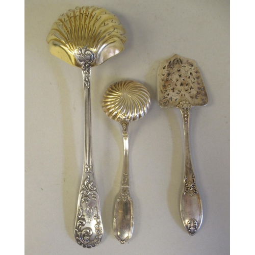 209 - Three 19thC Continental silver coloured metal items, viz. sifter spoon with a gilded shell shape bow... 