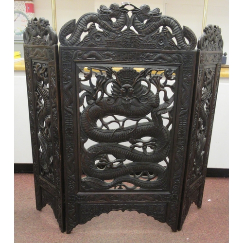 215 - A 20thC Oriental three-fold, dark stained, carved and pierced hardwood firescreen, decorated with dr... 