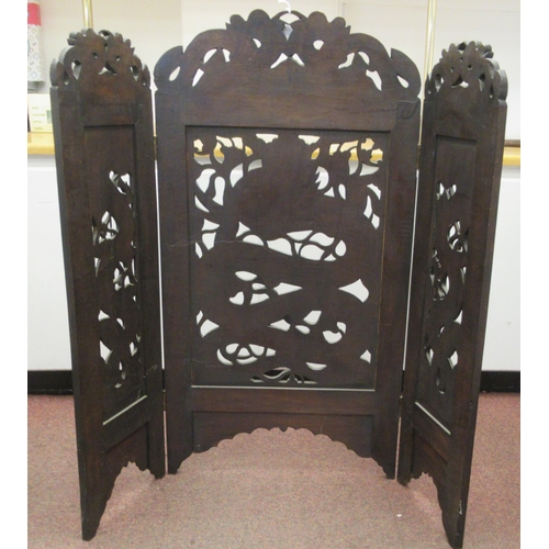 215 - A 20thC Oriental three-fold, dark stained, carved and pierced hardwood firescreen, decorated with dr... 