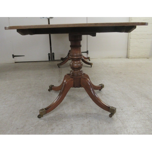 52 - An early 19thC mahogany dining table, comprising a pair of tip-top D-ends with reed carved edges, ra... 