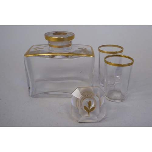 58 - A late 19thC French miniature gilded clear glass decanter with a pair of tot glasses, concealed in a... 