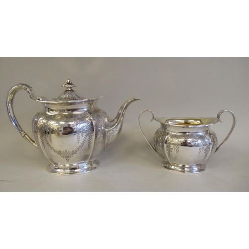 61 - An Edwardian four piece silver tea and coffee set of oval, panelled baluster form with engraved, tra... 