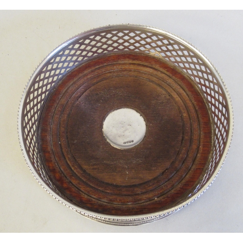 62 - A silver wine coaster with bead bordered, latticed sides, on a turned mahogany base  B&Co&n... 