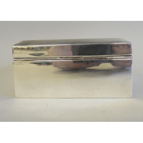 65 - A silver cigarette box with a cedar lining, straight sides and a chamfered, engine turned, hinged li... 