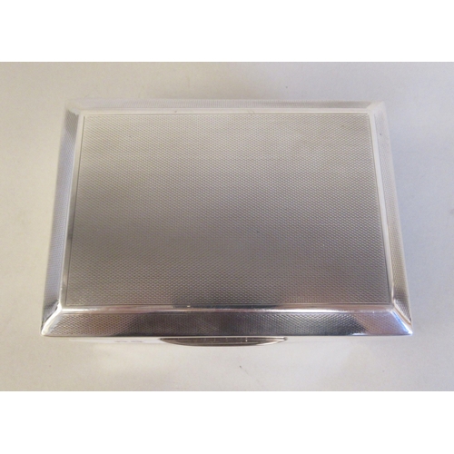 65 - A silver cigarette box with a cedar lining, straight sides and a chamfered, engine turned, hinged li... 