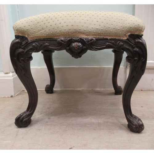 68 - A 19thC dark stained and profusely carved walnut framed stool of serpentine outline, the braided and... 