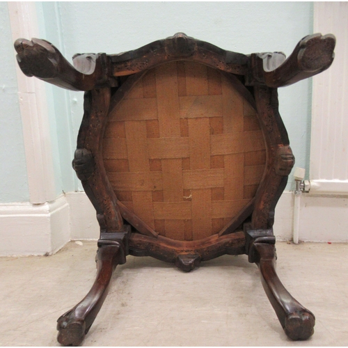 68 - A 19thC dark stained and profusely carved walnut framed stool of serpentine outline, the braided and... 