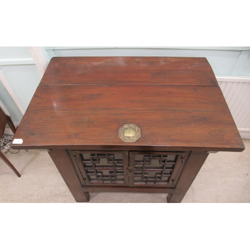 70 - A 20thC Korean elm altar design table/cabinet with a planked rising top, on brackets and an ornately... 