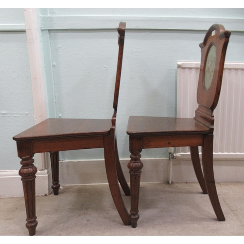 73 - A pair of mid/late 19thC oak framed hall chairs with shield backs, each set with a painted armorial ... 