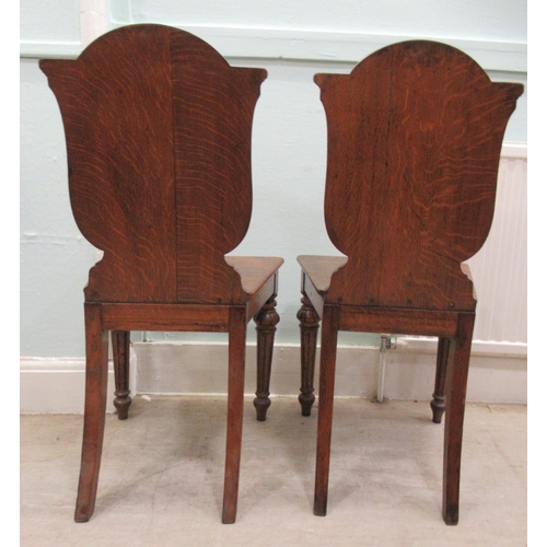 73 - A pair of mid/late 19thC oak framed hall chairs with shield backs, each set with a painted armorial ... 