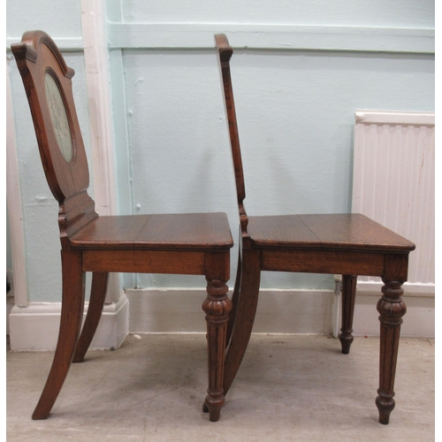 73 - A pair of mid/late 19thC oak framed hall chairs with shield backs, each set with a painted armorial ... 