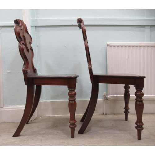 89 - A pair of mid 19thC mahogany hall chairs, the one-piece scroll carved backs with applied and painted... 