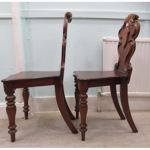 89 - A pair of mid 19thC mahogany hall chairs, the one-piece scroll carved backs with applied and painted... 