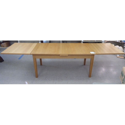 63 - A modern Danish oak finished draw leaf dining table, raised on square, tapered legs  30