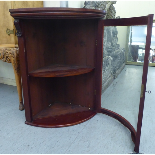 104 - A late 19thC mahogany hanging quadrant cupboard, the lockable glazed, full height door enclosing a s... 