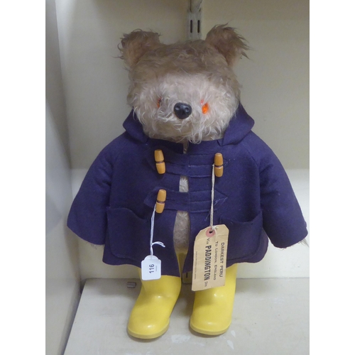 116 - A soft toy Paddington Bear, wearing a duffle coat and yellow Wellington boots  bears a label&nb... 