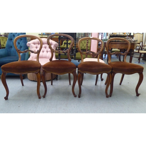 119 - A set of three and one matching late Victorian walnut framed balloon back dining chairs with carved ... 