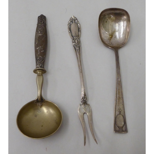 148 - Three items of white metal flatware: to include an Art Nouveau period spoon with a floral decorated ... 