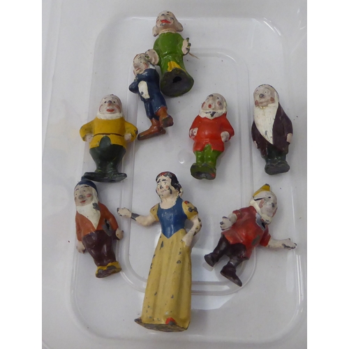 150 - A mid 20thC overpainted cast metal miniature figure, Snow White and the Seven Dwarfs 