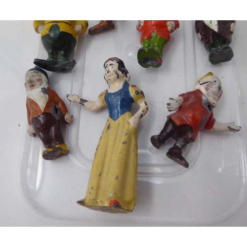 150 - A mid 20thC overpainted cast metal miniature figure, Snow White and the Seven Dwarfs 