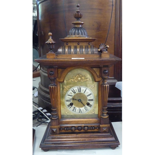 153 - An early 20thC walnut cased mantel clock; the 8 day movement faced by a Roman dial  19