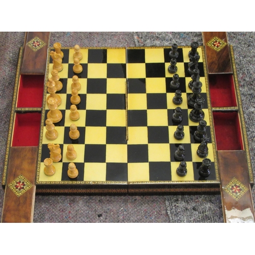 163 - A painted wooden chess set, contained in a marquetry, lacquered, folding box, incorporating a board ... 