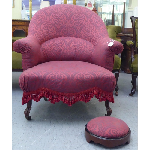 169 - An Edwardian tub style boudoir chair, upholstered in floral patterned maroon fabric with a fringed v... 