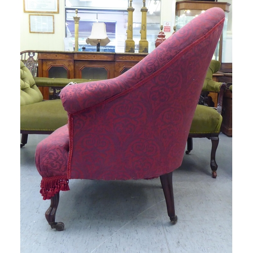 169 - An Edwardian tub style boudoir chair, upholstered in floral patterned maroon fabric with a fringed v... 