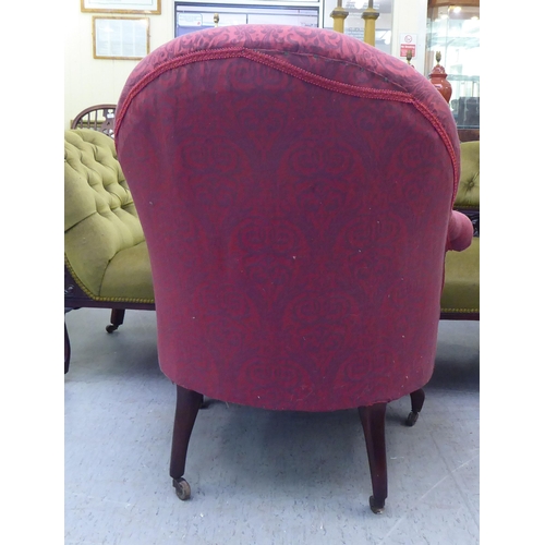 169 - An Edwardian tub style boudoir chair, upholstered in floral patterned maroon fabric with a fringed v... 